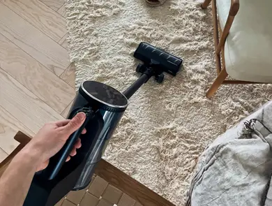 Trådløs støvsuger rengjør lyst gulvteppe hjemme