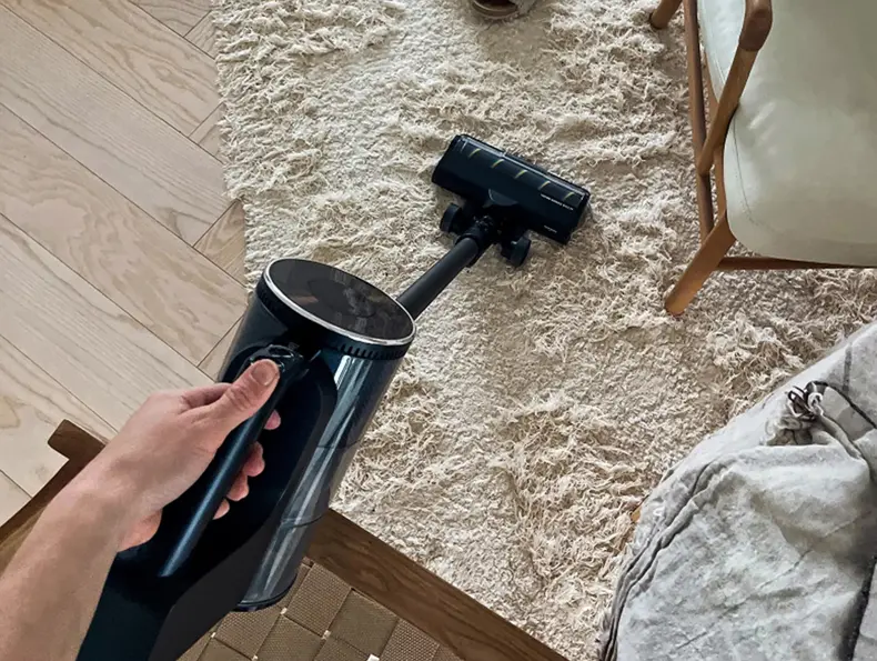 Trådløs støvsuger rengjør lyst gulvteppe hjemme