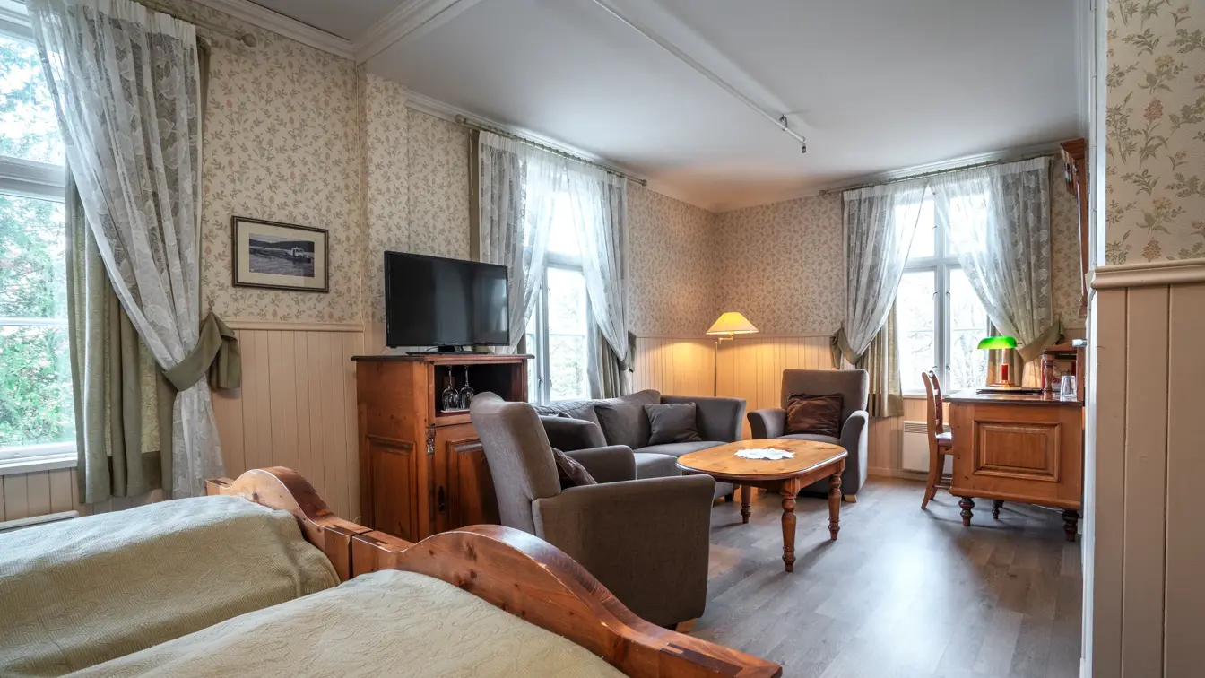 Business rom med dobbeltseng og TV med stor sofa-/sittegruppe i bakgrunnen