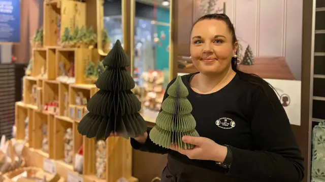 ansatt hos søstrene grene viser julepynten to grønne papirtrær