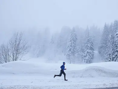 Mann i vinterlandskap som løper, sett i profil fra avstand