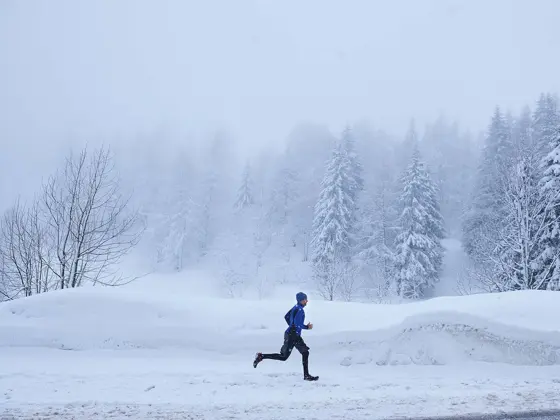 Mann i vinterlandskap som løper, sett i profil fra avstand
