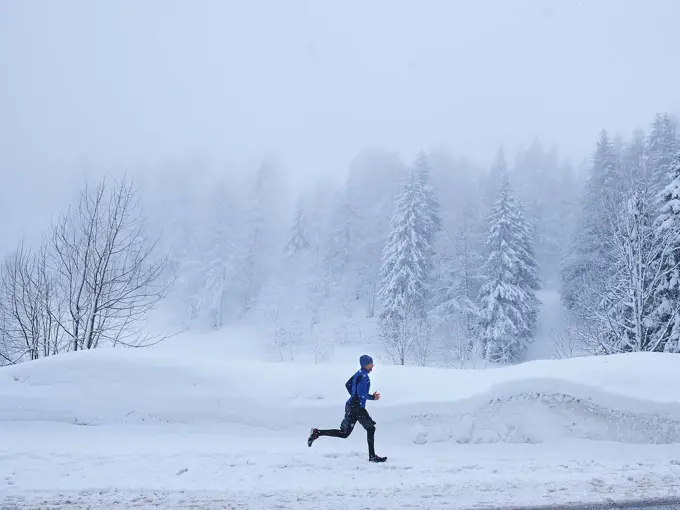 Mann i vinterlandskap som løper, sett i profil fra avstand