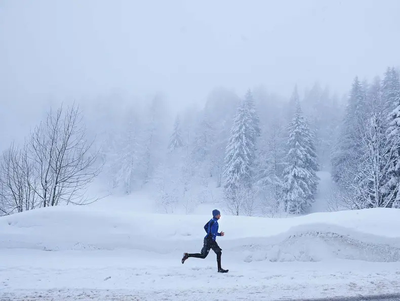 Mann i vinterlandskap som løper, sett i profil fra avstand