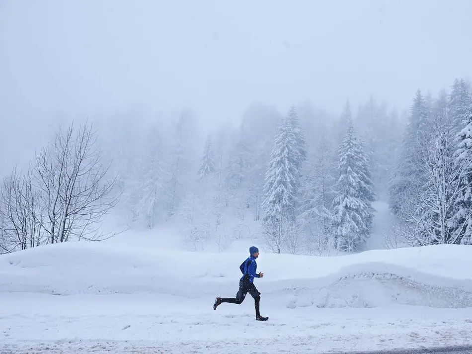 Mann i vinterlandskap som løper, sett i profil fra avstand