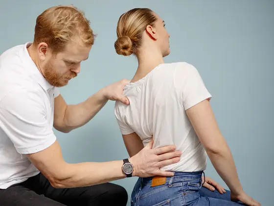 Mann kiropraktor som presser en dame i ryggen med hånden sin