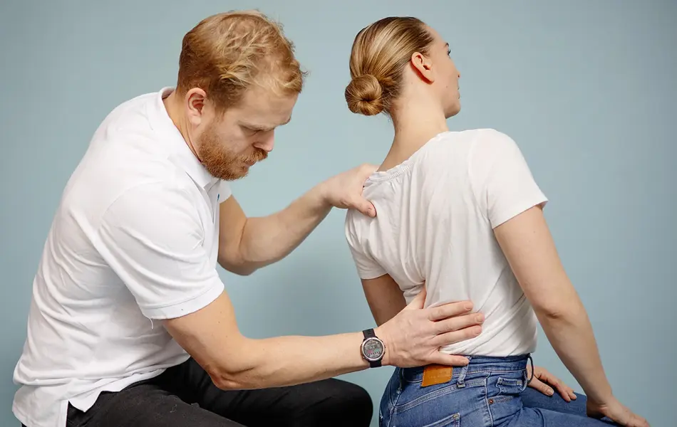 Mann kiropraktor som presser en dame i ryggen med hånden sin