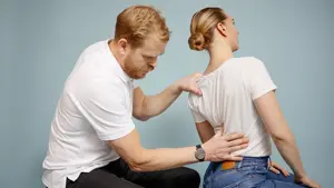 Mann kiropraktor som presser en dame i ryggen med hånden sin