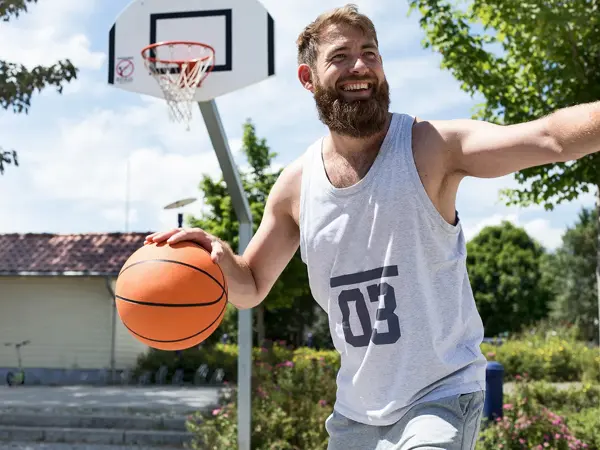 Mann med lys grå singlet med tallet 3 på spiller basket 