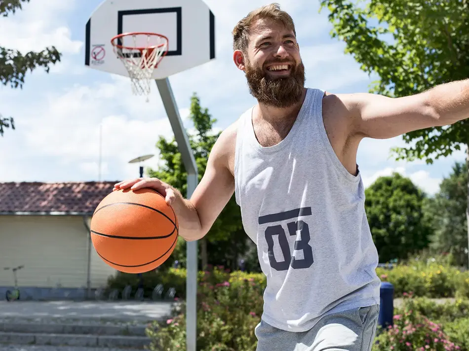Mann med lys grå singlet med tallet 3 på spiller basket 