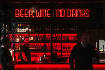 Liv & Røre Triaden bar, med en bartender bak baren og to menn foran baren
