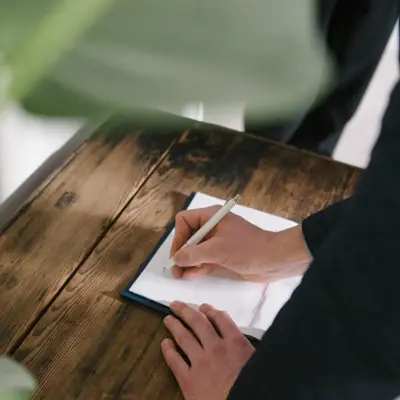 Hånd som signerer ark som ligger på trebord