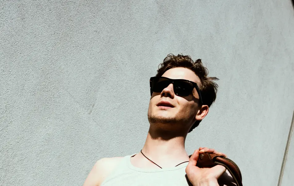 Mann med hvit singlett og skulderbag går ned trapp 