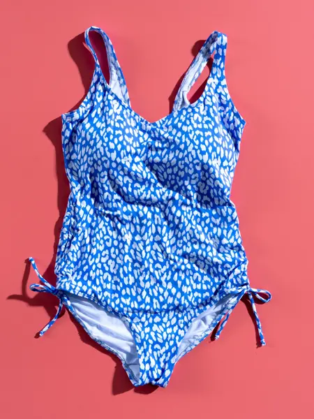 Blå og hvit spraglete badedrakt på rosa bakgrunn