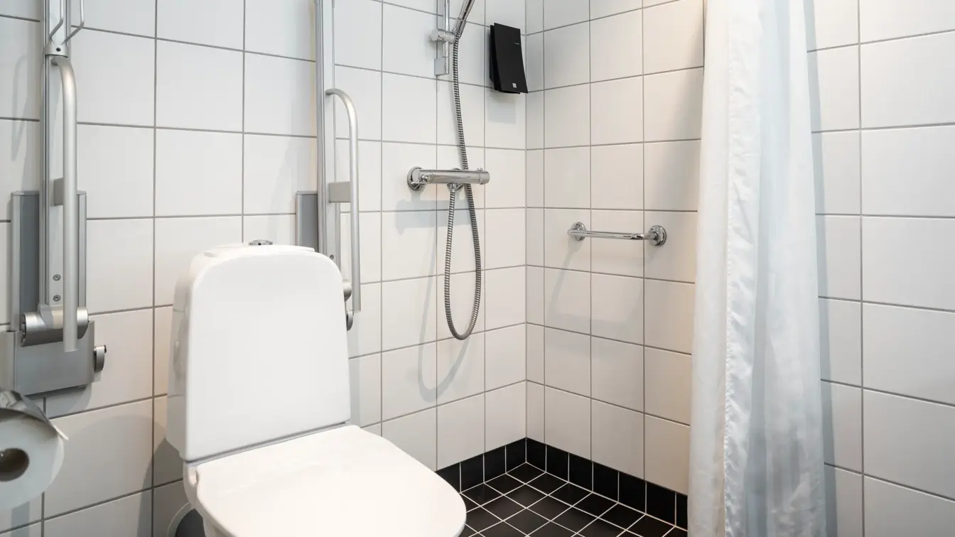 Hvite veggfliser, toalett, dusj, svarte gulvfliser