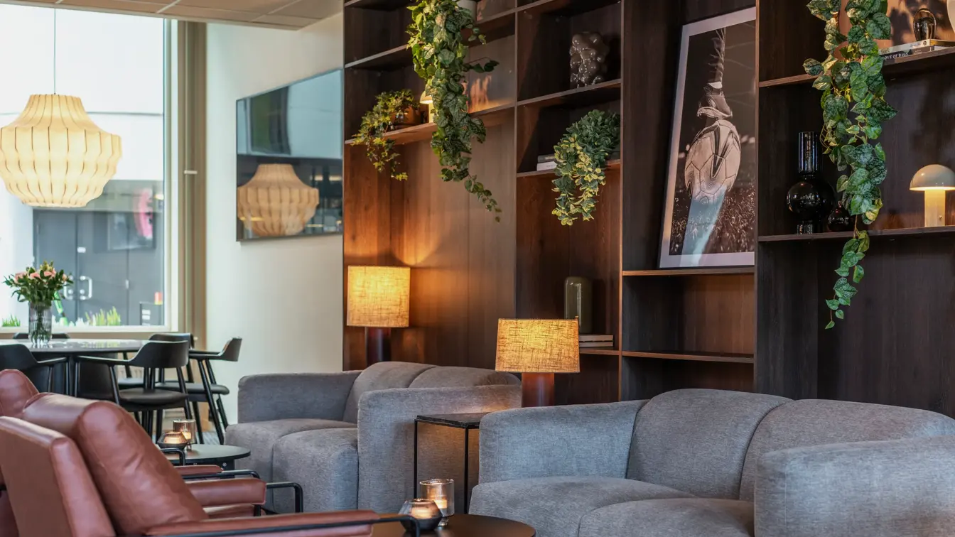 Sittegruppe i lobbyområde med stor bokhylle i treverk bak