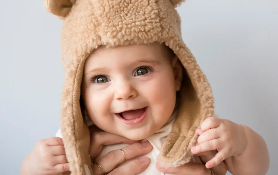 Caucasian mother holding baby daughter in fuzzy hat