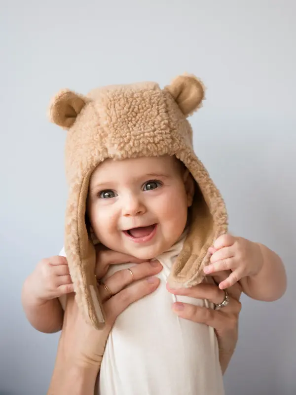 Caucasian mother holding baby daughter in fuzzy hat