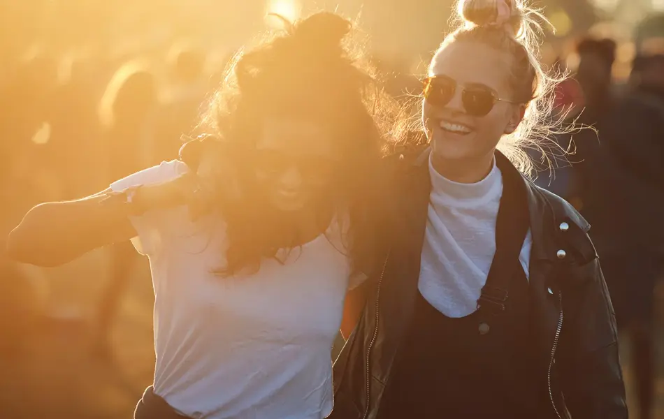 To venninner smiler og koser seg på festival