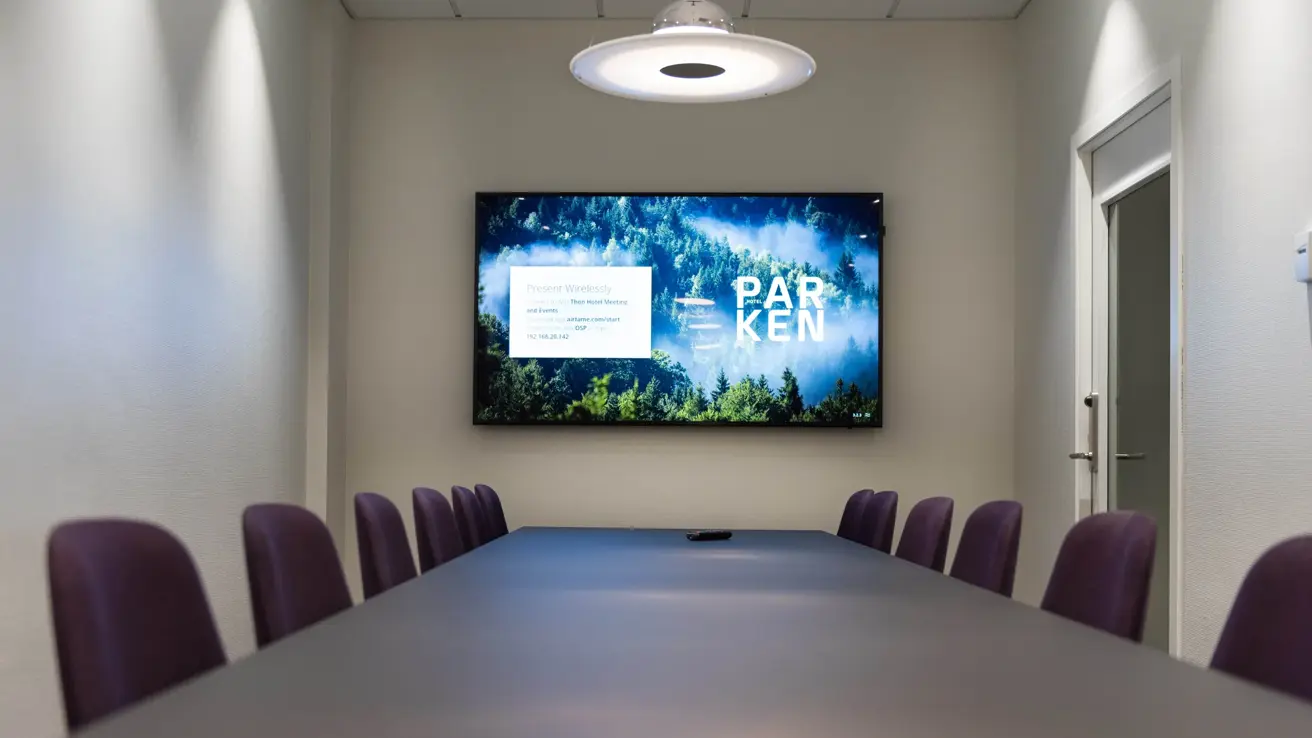 Bilde av konferanserom med bord og tv i enden