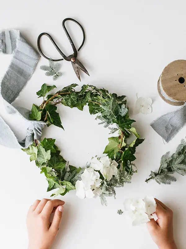 Krans av eføy og hvite blomster mot hvit bakgrunn