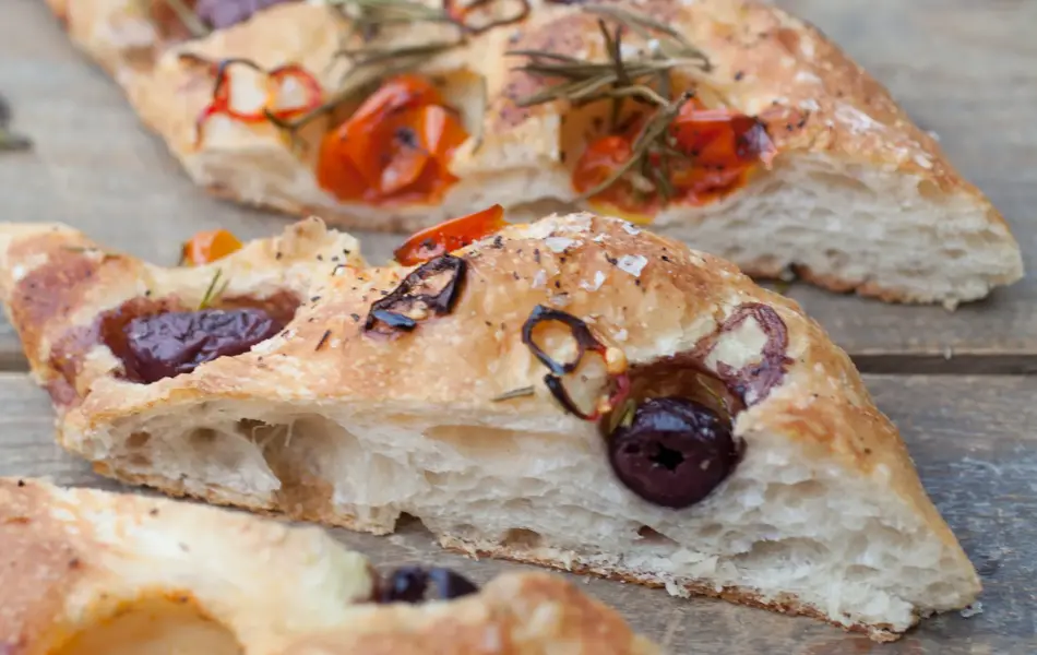 Italian bread made by an artisan baker topped with tomatoes, olives and herbs