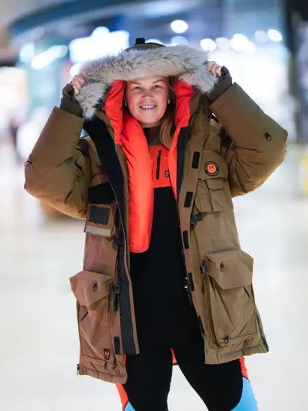 Jente med orangesekk og blådunjakke, og langrennski og slalåmski