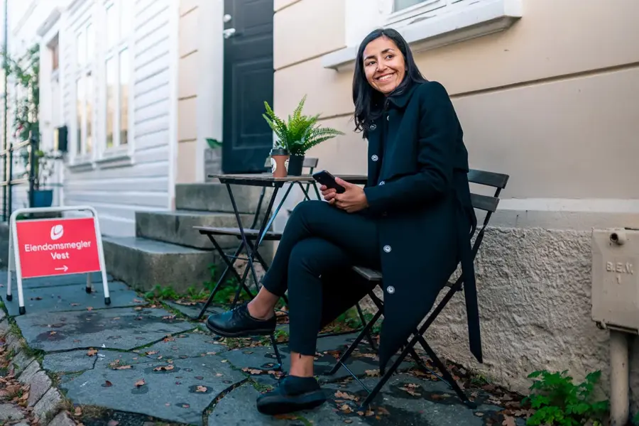 visning på hus og dame som sitter på stol utenfor