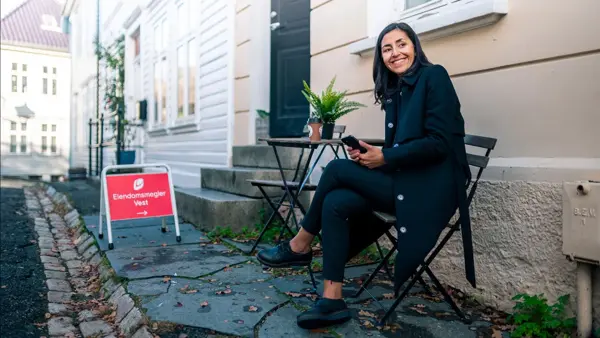 visning på hus og dame som sitter på stol utenfor