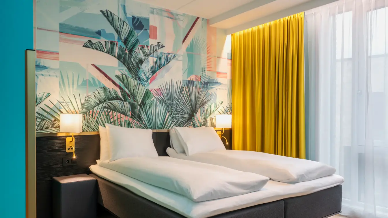 Dobbeltseng og fargerik palmetapet i standard HCP rom på Thon Hotel Storo