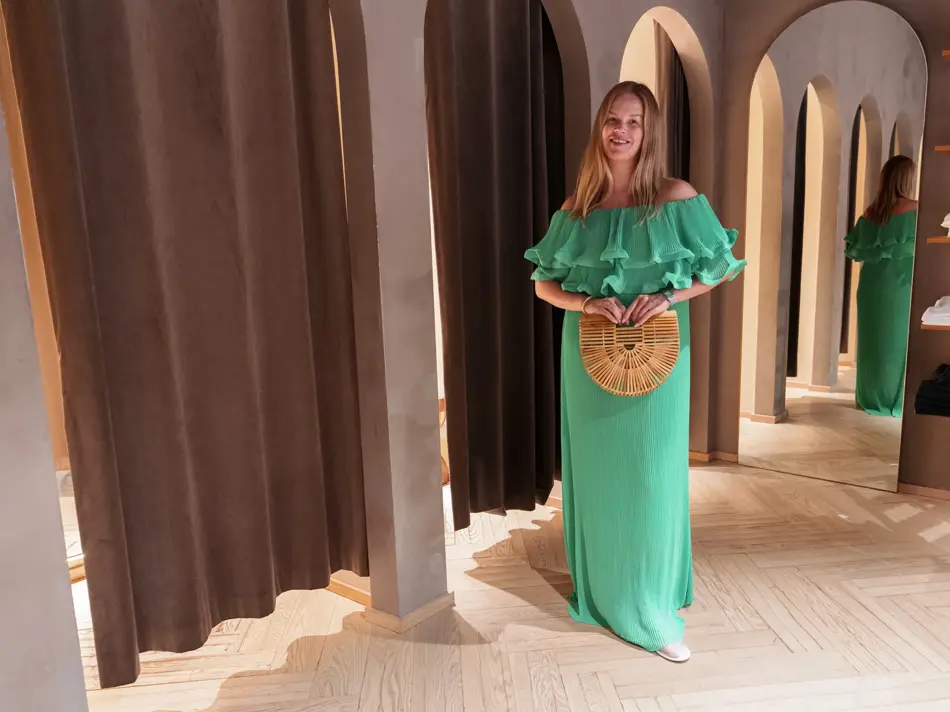 Damemodell i grønn lang kjole og stråveske