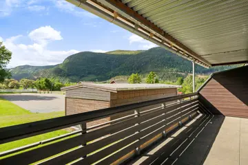 Flå leil H0104 med utsikt fra overbygget balkong mot bod, idrettsbane og fjell, Hallingtunet i Flå.
