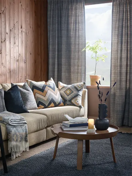 Sofagruppe med blå gardiner og trevegger i bakgrunn