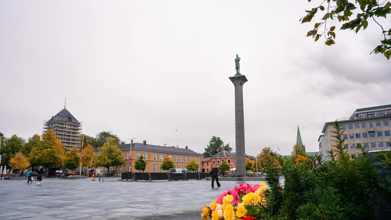 Torvet i sentrum med bygninger og fargerike trær og blomster rundt