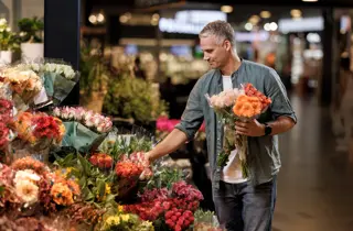 En mann står og velger blomster hos en blomsterbutikk