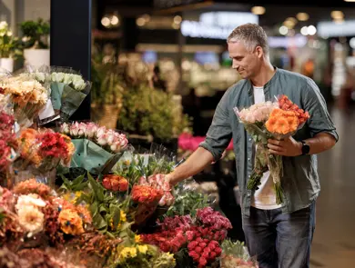 En mann står og velger blomster hos en blomsterbutikk
