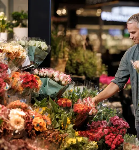 En mann står og velger blomster hos en blomsterbutikk