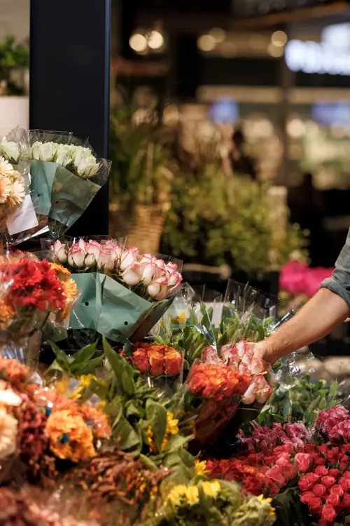 En mann står og velger blomster hos en blomsterbutikk