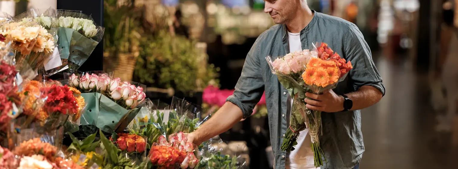 En mann står og velger blomster hos en blomsterbutikk