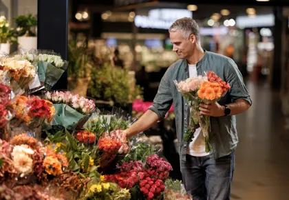 En mann står og velger blomster hos en blomsterbutikk