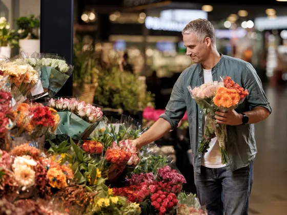En mann står og velger blomster hos en blomsterbutikk