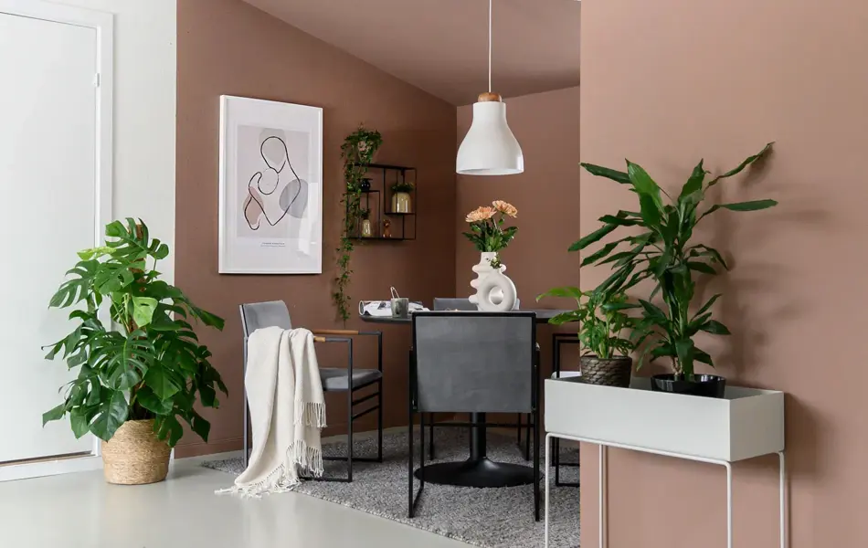 Stue med brun vegg og grønnplanter med en sittegruppe i et hjørne