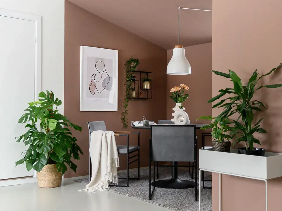 Stue med brun vegg og grønnplanter med en sittegruppe i et hjørne