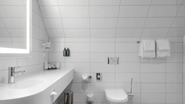 Flislagt bad med servant, speil og toalett. 