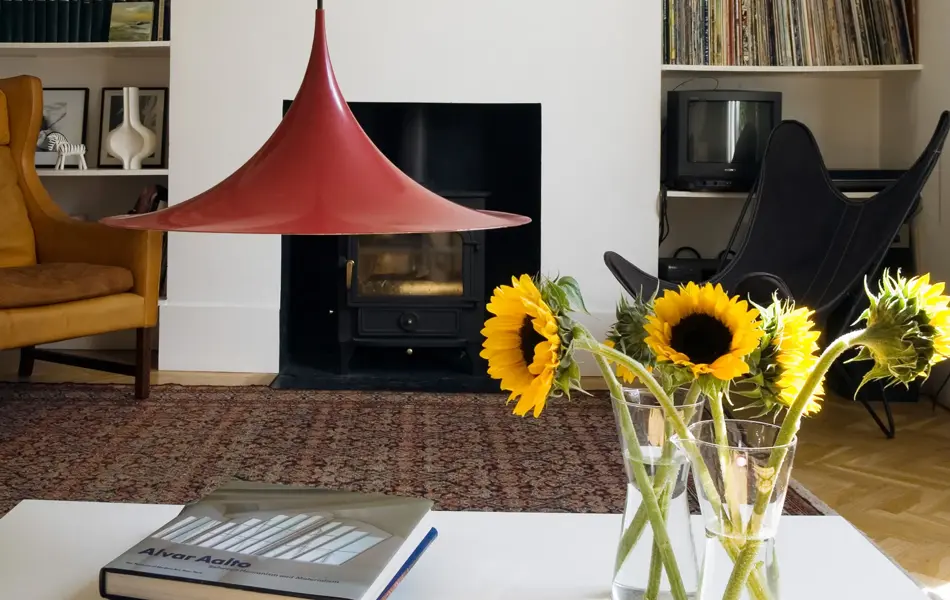 Stue med rød statementlampe, bord med gule solsikker og hyller med LP-plater og bøker i bakgrunnen 