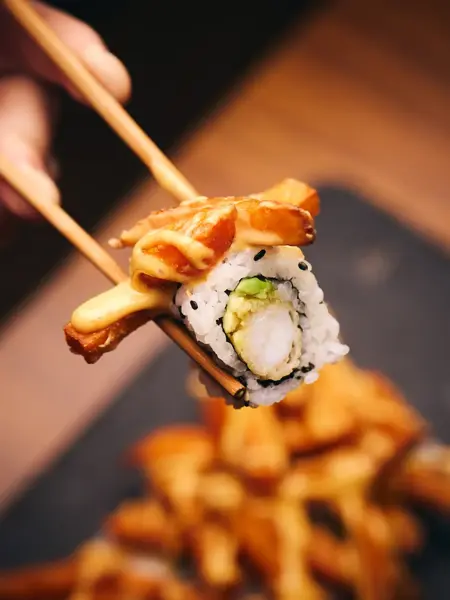 hånd som holder spisepinner med sushi fra sumo