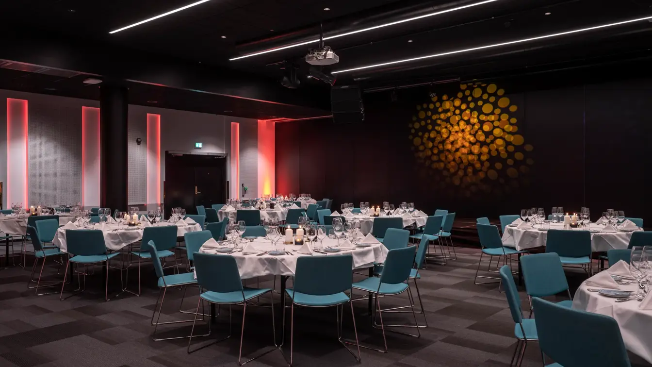 Kveldsstemning, bankett, runde bord med hvite duker og stearinlys. Turkise stoler.