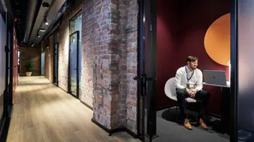 En gang med kontorer, og en mann som sitter inne i et av kontorene