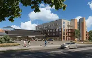 Fasadebilde av Triaden Helsehus på Lørenskog. Helsehuset vises i forkant og i bakgrunnen ser man kjøpesenteret Thon Senter Triaden.