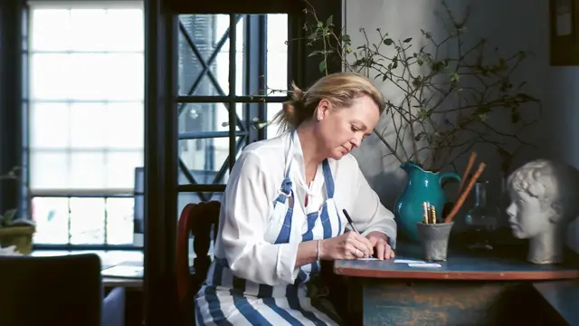 kvinne som sitter ved skrivebord og skriver